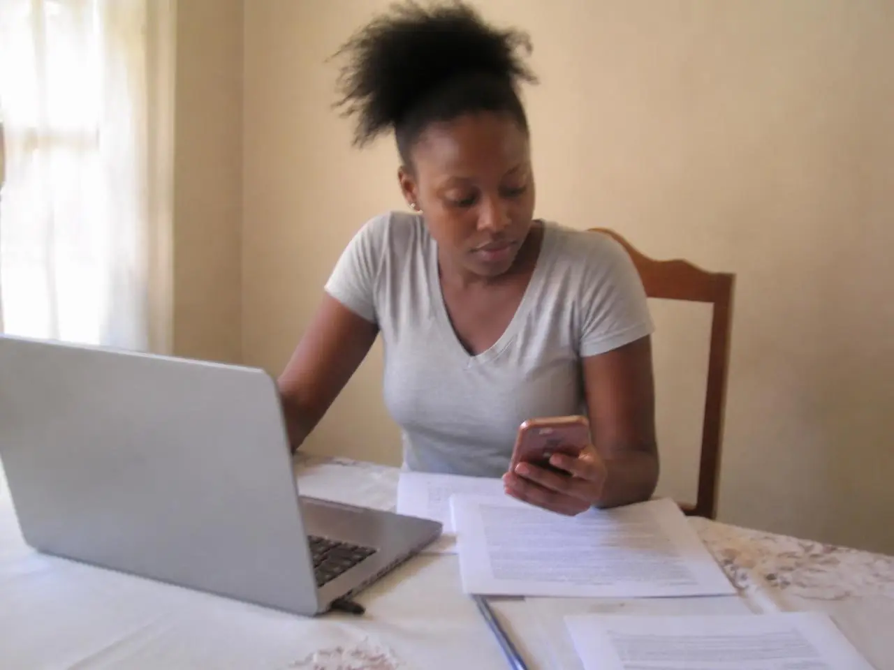 Mulher em casa a preparar a candidatura com computador e documentos impressos